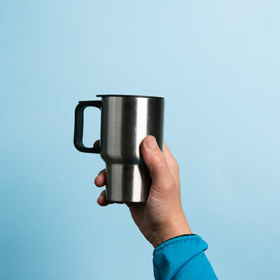 a-man-holds-a-thermos-mug-high-in-his-hand-on-blue-2022-02-14-19-13-28-utc